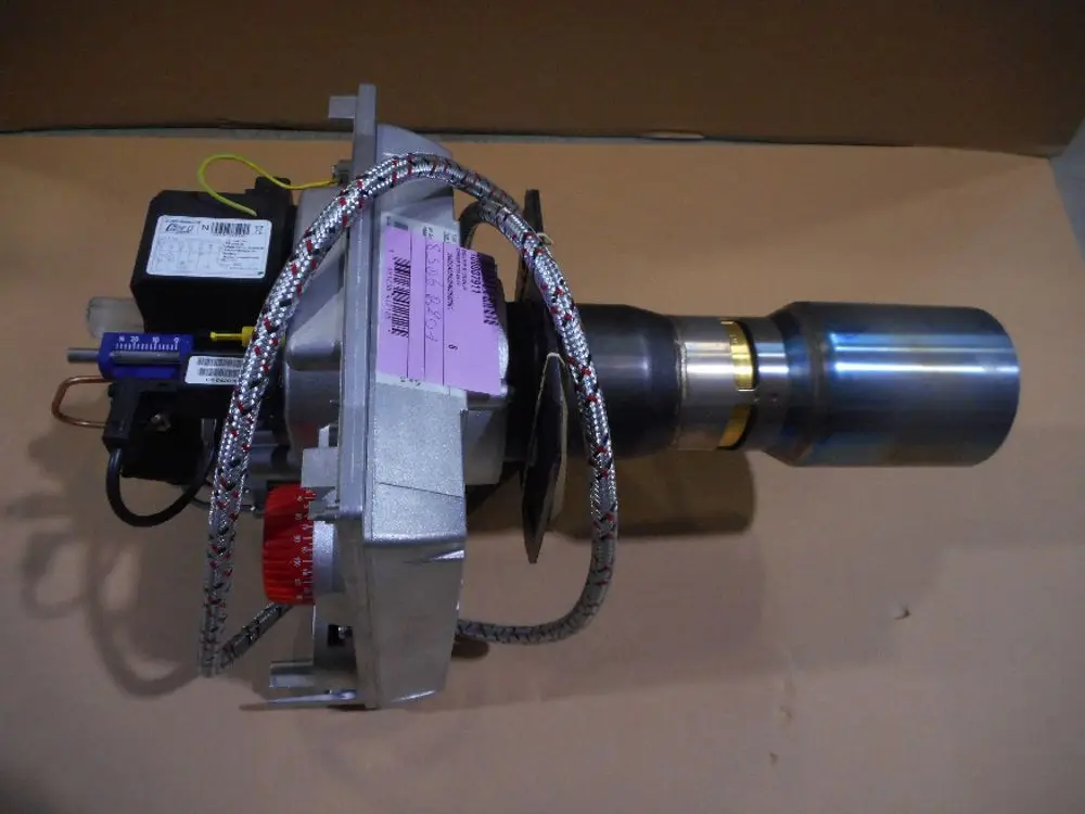 Remeha-Komponente mit metallischem Gehäuse, Schlauchleitungen und elektrischen Anschlüssen. Das Teil hat einen konischen Auslass und ist auf einer Pappe platziert.